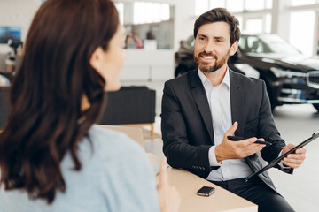 Car salesman showing a contract to a customer in a dealership