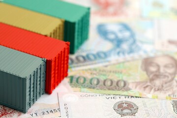 Fototapeta premium Vietnamese dong currency money bills and toy cargo containers. The concept of shipping and logistics