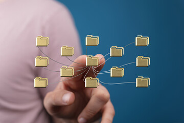 Image depicting a hand interacting with a network of gold folders, symbolizing data connection and...