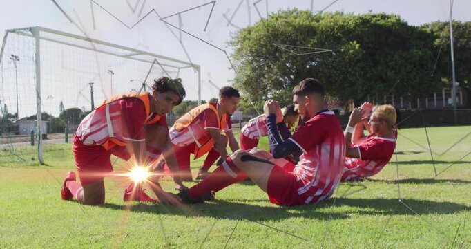 Seven soccer players pairing in front of goal and doing partner crunches for fitness training