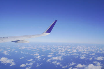 Obraz premium Airplane wing above the clouds during flight, view from airplane window.