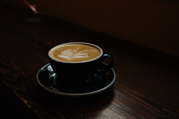 Large cup of cappuccino with a beautiful latte art on a wooden table. Delicious coffee with plant-based milk made from high-quality coffee beans.