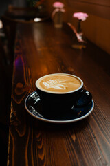 Large cup of cappuccino with a beautiful latte art on a wooden table. Delicious coffee with plant-based milk made from high-quality coffee beans.
