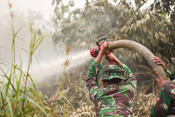 Indonesian soldiers fight intense land fires in Kalimantan using high-pressure hoses, battling thick smoke and annual haze that severely disrupt daily life across many affected regions.