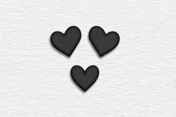 Obraz premium Three unique black hearts arranged on a textured white background symbolizing deep emotional connections and unifying love in a minimalist style captured with clarity