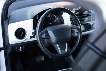 Black leather dashboard, climate control, speedometer, display, decoration. Car steering wheel. Electric car interior with steering wheel