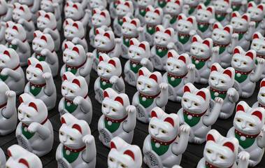 Maneki-neko cat waving his paw. Gold fortune cats wave paws animation. White maneki neko Japanese and Chinese figure fortune and luck cat. Lucky and fortune cats waving for luck.