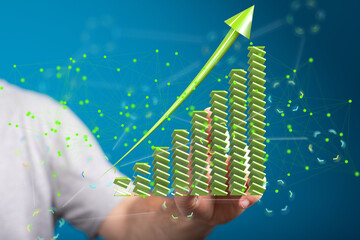 Stock photo of a hand holding a 3D green upward trending graph, symbolizing growth and success.