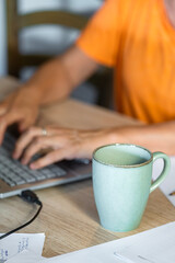 Coffee cup in foreground and laptop out of focus