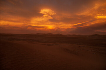 Fiery red dunset over desert landscape in Iran. 