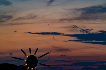 Minimalistic sunset scene featuring a stylized artificial sun glowing above a calm, empty horizon. The surreal landscape showcases warm gradient tones, soft light, and abstract composition. No people 