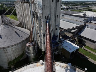 Aerial view of aging concrete silos interconnected by rusty metal conduits under a hazy sky near 2885 E Sharon Rd, Cincinnati, Ohio, United States.