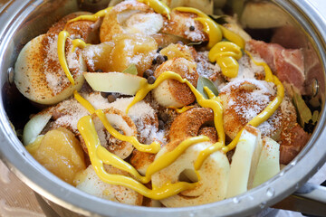 Ingredients for shish kebab are marinating in a pot, creating an appetizing look. Meat with onions, mustard, and spices is waiting to be cooked.