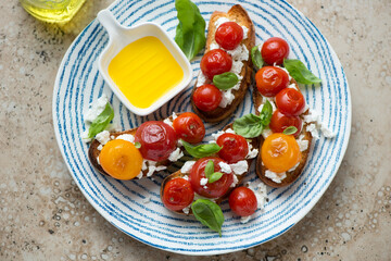 Blue and white plate with roasted tomato bruschettas, horizontal shot on a beige granite background, high angle view