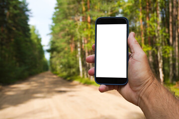 Hand holding smartphone with white screen in forest road background. route building and navigation in the mobile app.