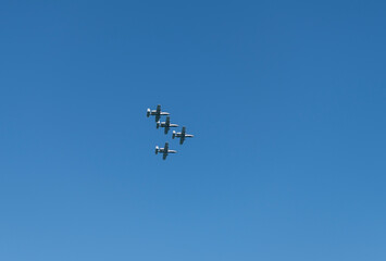 Military air force fighter jet airplane in full flight against blue sky. Four fighter jet in V shape in sky. Squadron. Air Force Day. Aircraft squadron on a mission. US air force
