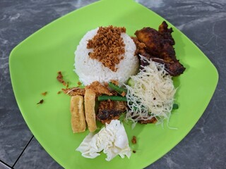 A plate of rice with fried chicken as a side dish