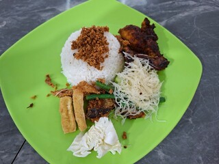 A plate of rice with fried chicken as a side dish