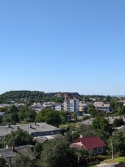 Obraz premium Panoranmic view of a small town with residential areas and green hills in the background. Daytime urban scene. 