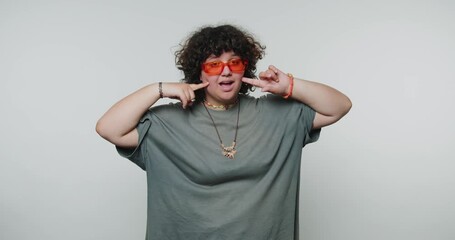 expressive young woman poses joyfully with hands on cheeks, showcasing playfulness and a vibrant sense of personality on white background