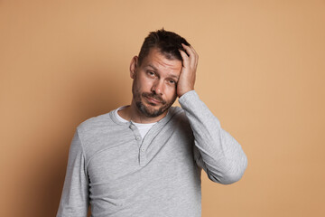 Man suffering from hangover on beige background