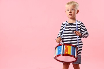 Cute little boy playing drum on pink background. Space for text