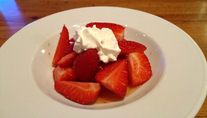 Sliced strawberries in a bowl, topped with whipped cream