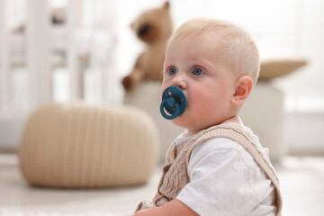 Cute baby with pacifier in light room. Space for text