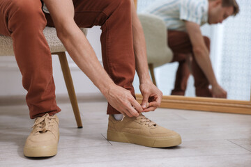 Getting ready. Young man putting on stylish shoes at home, closeup