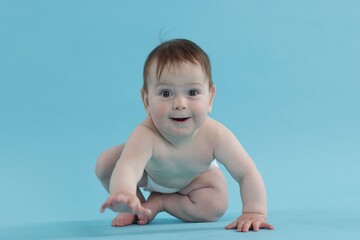 Cute little baby crawling on light blue background