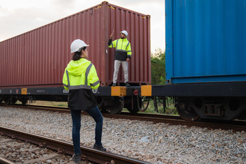 Foreman checking inventory or task details on freight train cars and shipping containers. Logistics...