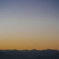 Fototapeta premium Pastel-colored twilight sky with a purple and orange gradient over a dark mountain silhouette.
