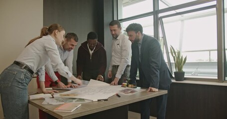 A diverse team of business professionals collaborates on a project, reviewing blueprints and engaging in teamwork. - Powered by Adobe