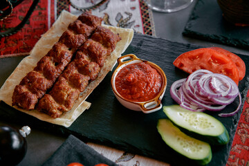 Savory Grilled Kebabs Served with Fresh Vegetables and Spicy Tomato Sauce on a Rustic Slate Platter Enhancing the Culinary Experience