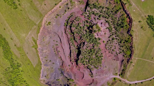 The extinct volcano from Racos, Romania. Aerial view of volcanic crater covered by green meadow and forest. View inside Volcano with lush vegetation in summer. Volcano ridge with vegetation. 