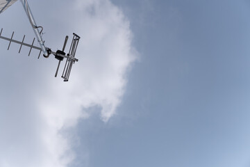 Old television antenna against a blue sky with white clouds. Retro communication technology concept with copy space
