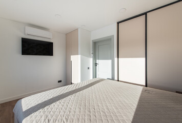 Obraz premium Bedroom Interior. Beautiful Sunlight. King Size Bed and Windows. TV Screen and AC on the Wall.