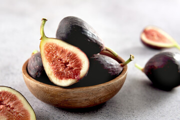 Fresh figs in a wooden bowl on a gray background.