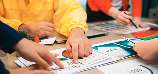 A dynamic team engages in a creative brainstorming session, collaborating on design concepts and analyzing colorful charts and drafts on a modern workspace. SACTR