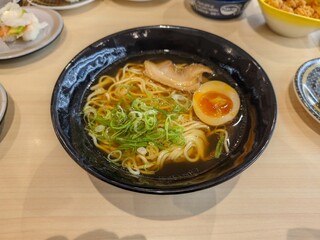 Japanese ramen noodle soup with egg, scallions, and broth in a black bowl