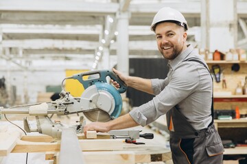 Carpenter cutting wooden plank with circular saw in workshop