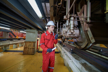 Fototapeta premium Worker conducts maintenance on train wheels inside repair facility in the morning hours
