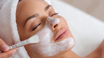 A woman enjoys a facial treatment at a tranquil spa. Aesthetician applies a soothing mask to her face, promoting relaxation and skin nourishment.