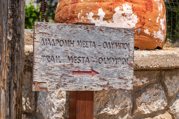 Hiking trail sign pointing the direction from Mesta to Olympoi village in english and greek. Chios...