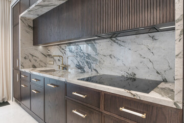 Stylish kitchen with marble countertops and dark wood cabinets. Elegance and grace are 
combined with a minimalist design.