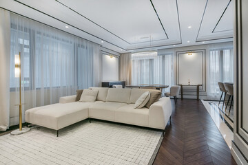 Naklejka premium Modern interior design of the living room with elegant furniture and large windows filling the space with soft natural light.