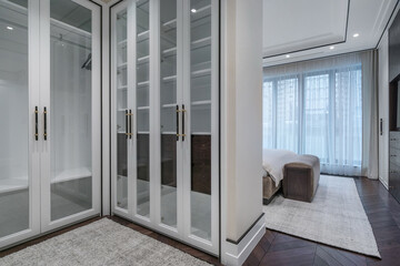 The elegant design of the bedroom with panoramic windows and the wardrobe with modern finishes and stylish solutions for storing things in a modern space.
