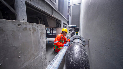 Construction worker repairing pipes in industrial area during daytime