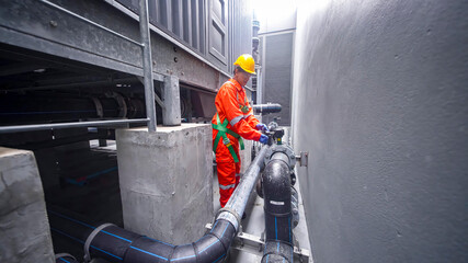 Worker checks pipes at industrial facility during daytime maintenance procedures