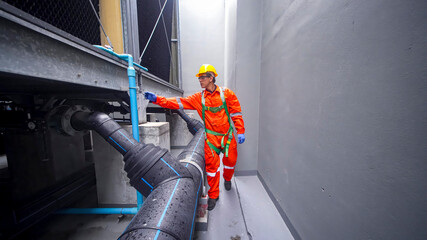 Worker inspects industrial pipes in safety gear during daytime